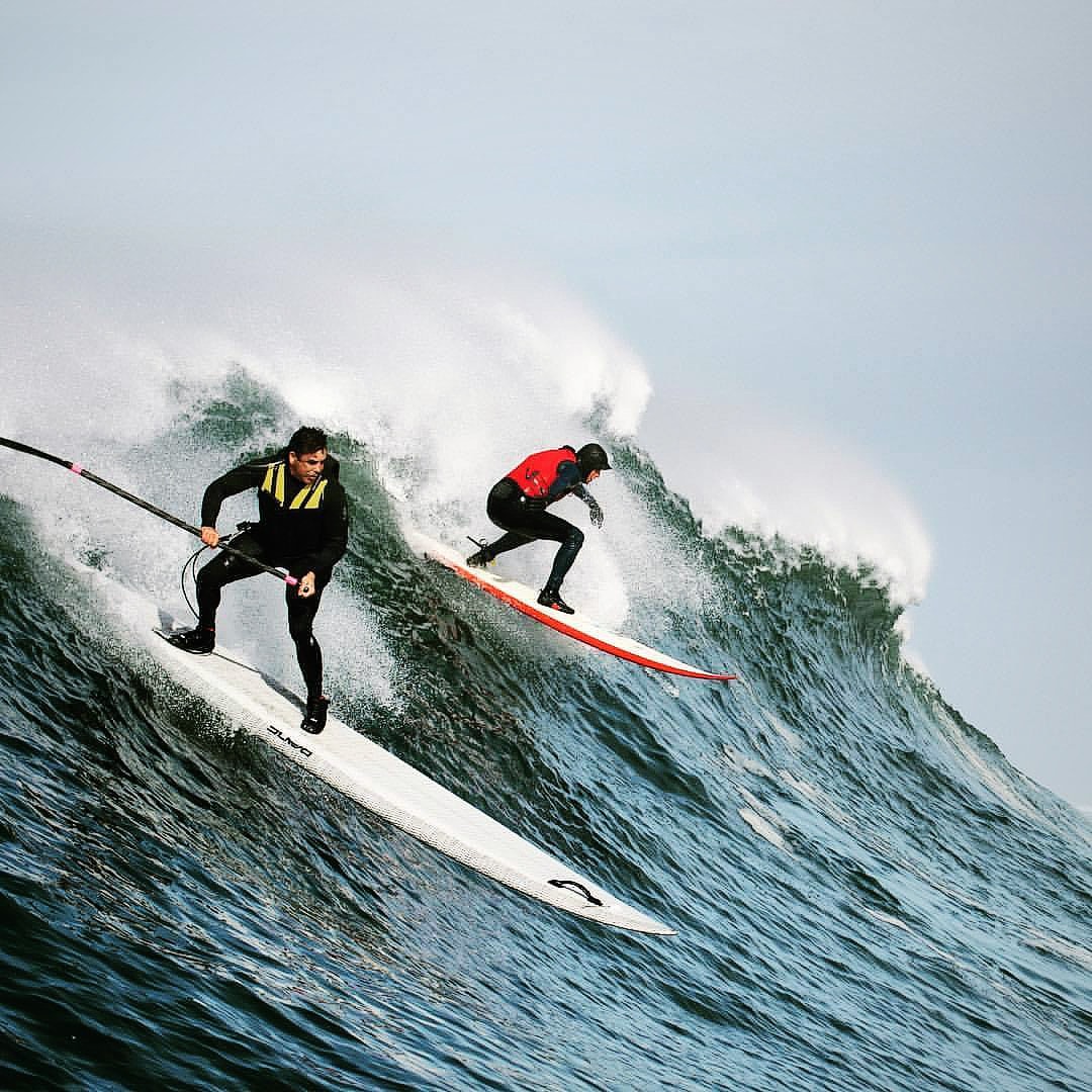 Surfer on stand up paddle board riding a large ocean wave
