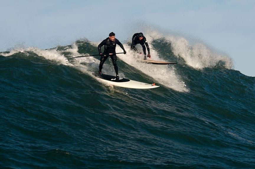 Two surfers riding large ocean waves