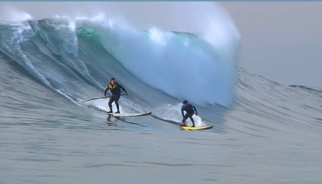 Surfers riding a massive wave